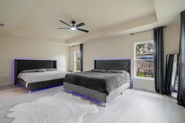 bedroom featuring a tray ceiling, light hardwood / wood-style flooring, and ceiling fan