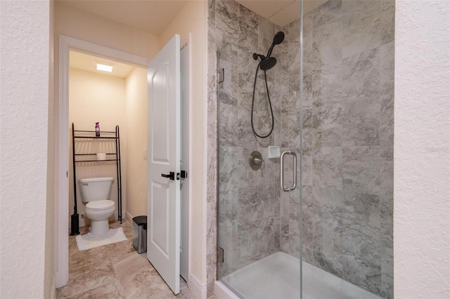 bathroom featuring toilet and a shower with shower door