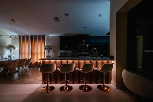 kitchen featuring sink, tasteful backsplash, a kitchen bar, kitchen peninsula, and stainless steel appliances