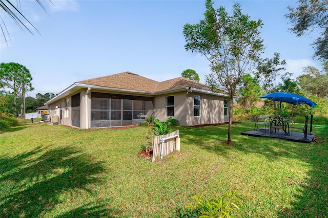 back of property featuring a lawn, a patio area, and a sunroom