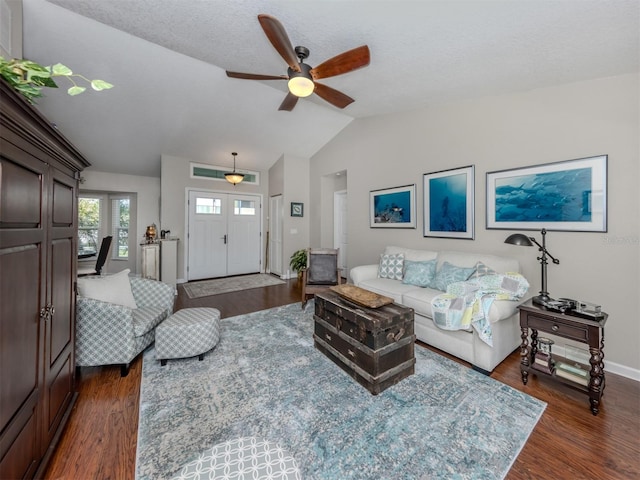 living room with a textured ceiling, vaulted ceiling, ceiling fan, and dark wood-type flooring