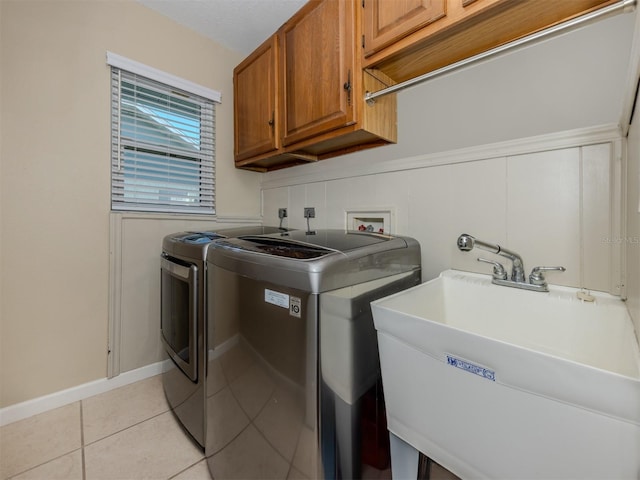 washroom featuring cabinets, light tile patterned floors, sink, and washing machine and dryer