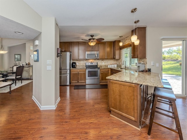 kitchen with sink, a breakfast bar area, decorative light fixtures, kitchen peninsula, and stainless steel appliances