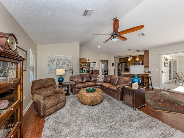 living room with a textured ceiling, dark wood-type flooring, ceiling fan, and lofted ceiling