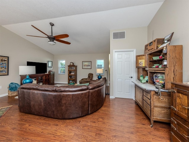 living room with vaulted ceiling, ceiling fan, and dark wood-type flooring