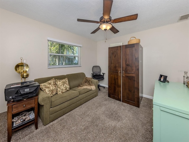 carpeted living room featuring ceiling fan and a textured ceiling