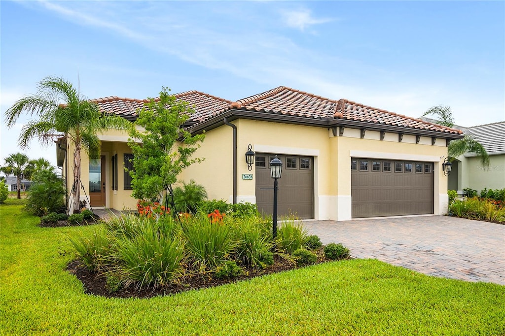 mediterranean / spanish-style house with a garage and a front lawn