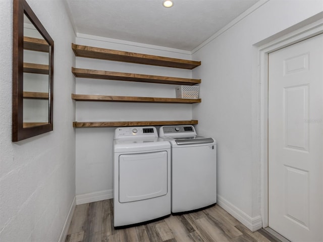 laundry room with light hardwood / wood-style flooring, washer and clothes dryer, and ornamental molding