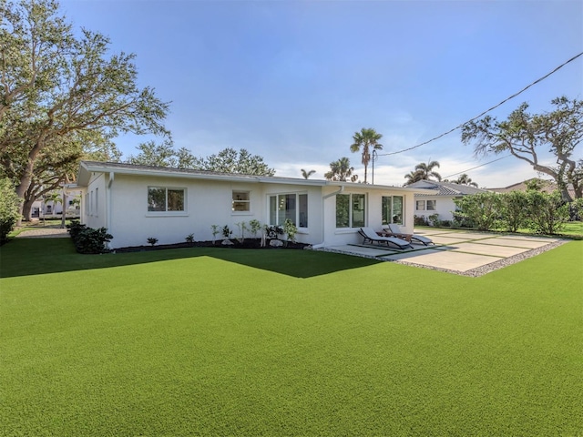 back of house featuring a lawn and a patio area