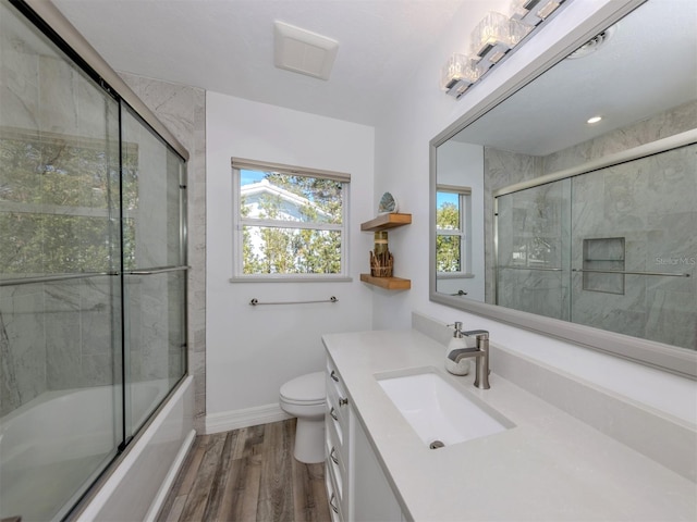 full bathroom with hardwood / wood-style flooring, combined bath / shower with glass door, toilet, and vanity