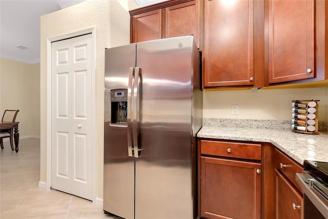 kitchen featuring appliances with stainless steel finishes, light tile patterned floors, light stone counters, and crown molding