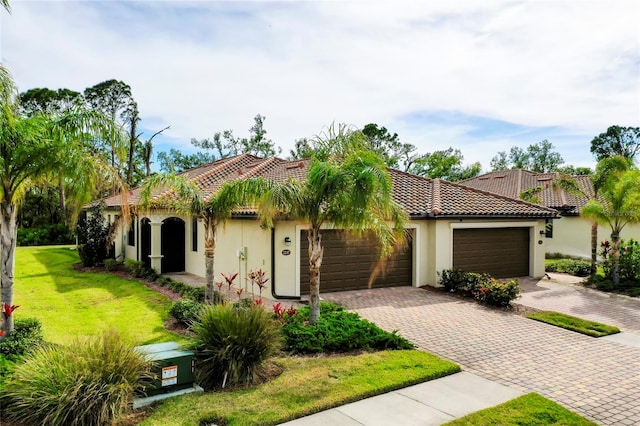 mediterranean / spanish-style home featuring a garage and a front lawn