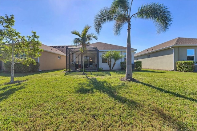 rear view of property with a yard and glass enclosure