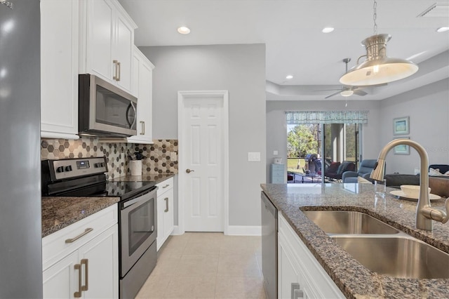 kitchen with appliances with stainless steel finishes, sink, backsplash, dark stone counters, and white cabinets