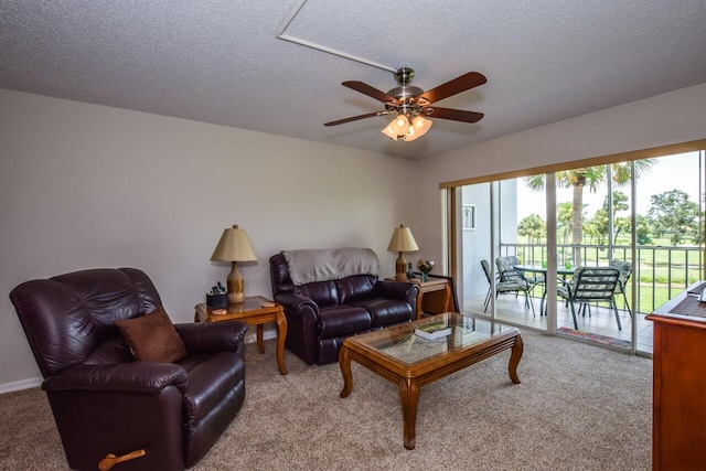 living room featuring ceiling fan, carpet floors, and a textured ceiling