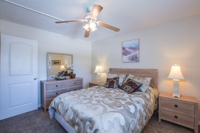 bedroom with ceiling fan, dark carpet, and a textured ceiling