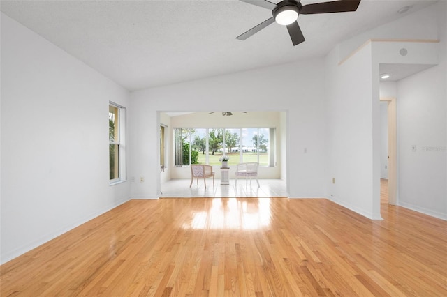 unfurnished living room with a textured ceiling, ceiling fan, lofted ceiling, and light wood-type flooring