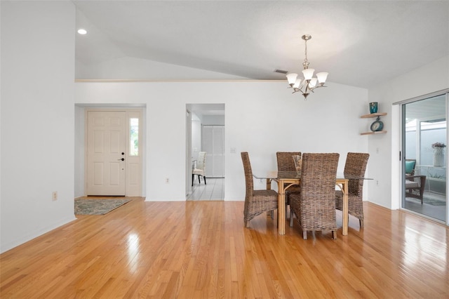 dining room with light hardwood / wood-style floors, vaulted ceiling, and an inviting chandelier