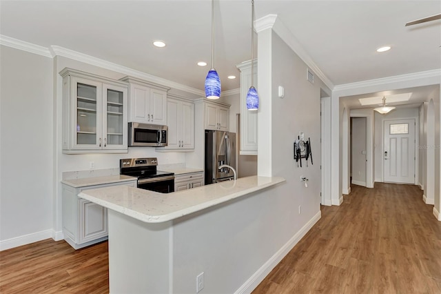 kitchen featuring pendant lighting, crown molding, light hardwood / wood-style flooring, appliances with stainless steel finishes, and kitchen peninsula