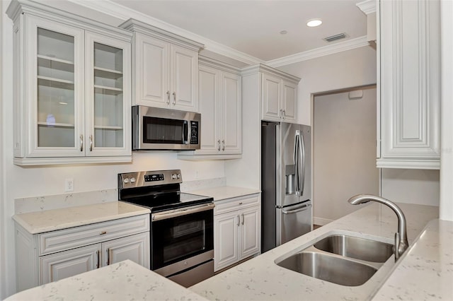 830 The Esplanade N Unit 203, Venice, FL 34285 - kitchen with appliances with stainless steel finishes, a sink, light stone countertops, glass insert cabinets, and ornamental molding