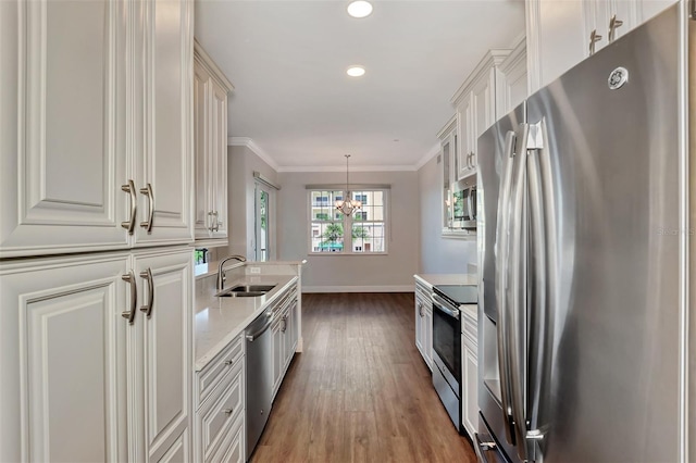 kitchen featuring dark wood-type flooring, sink, hanging light fixtures, white cabinetry, and stainless steel appliances