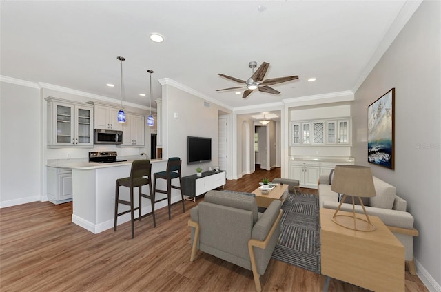 living room featuring hardwood / wood-style flooring, ceiling fan, and crown molding