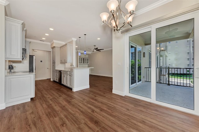 kitchen featuring ceiling fan with notable chandelier, decorative light fixtures, dark hardwood / wood-style floors, and ornamental molding