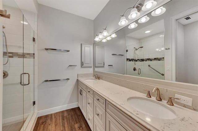 830 The Esplanade N Unit 203, Venice, FL 34285 - bathroom with a stall shower, double vanity, wood finished floors, and baseboards