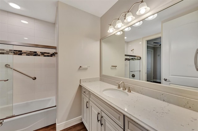 bathroom featuring wood-type flooring, vanity, and bath / shower combo with glass door