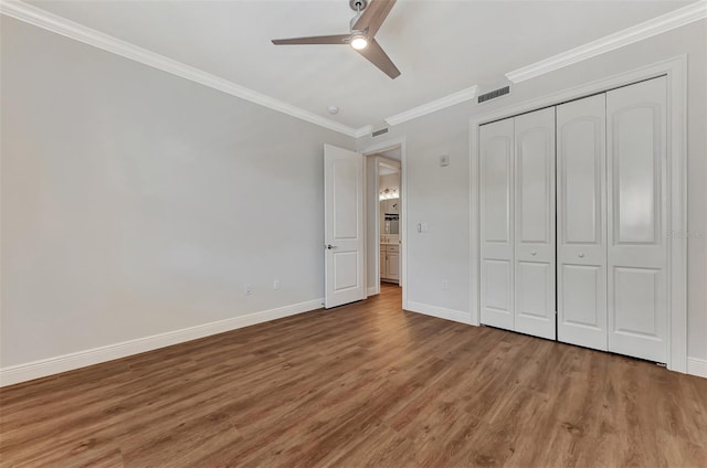 unfurnished bedroom featuring hardwood / wood-style floors, ceiling fan, crown molding, and a closet