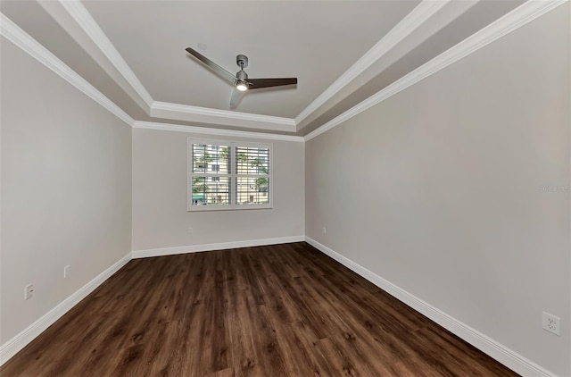 empty room featuring a tray ceiling, crown molding, ceiling fan, and dark wood-type flooring