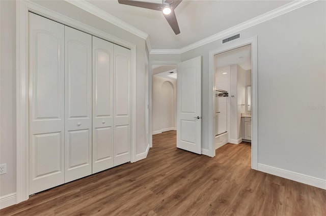 unfurnished bedroom featuring crown molding, a closet, ceiling fan, and hardwood / wood-style flooring