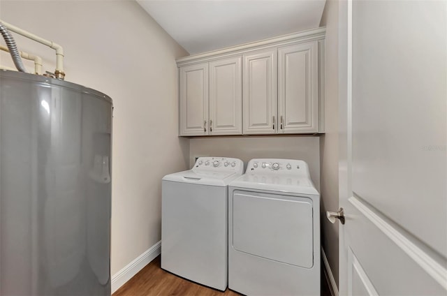 clothes washing area with washer and clothes dryer, water heater, cabinets, and light hardwood / wood-style flooring