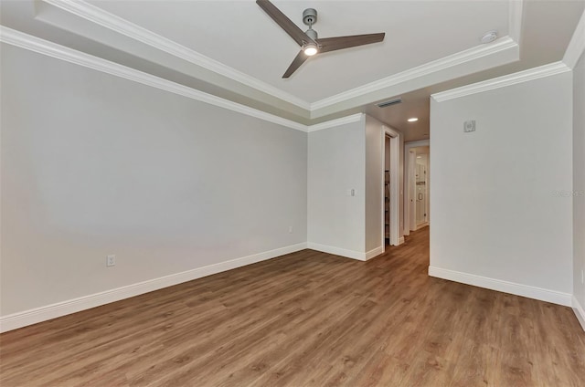 spare room featuring hardwood / wood-style floors, ceiling fan, ornamental molding, and a tray ceiling