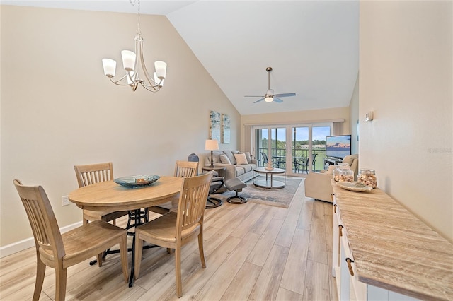 dining space with ceiling fan with notable chandelier, light hardwood / wood-style floors, and high vaulted ceiling