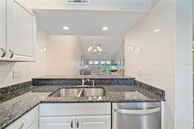 kitchen featuring sink, an inviting chandelier, stainless steel dishwasher, lofted ceiling, and white cabinets