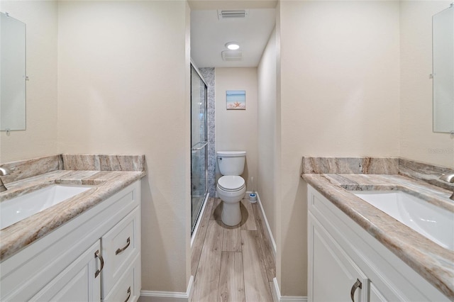 bathroom featuring walk in shower, hardwood / wood-style floors, vanity, and toilet