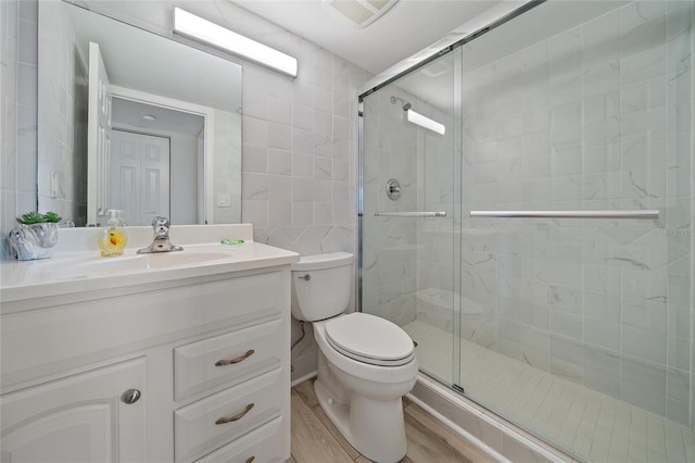 bathroom with hardwood / wood-style floors, vanity, a shower with shower door, and toilet