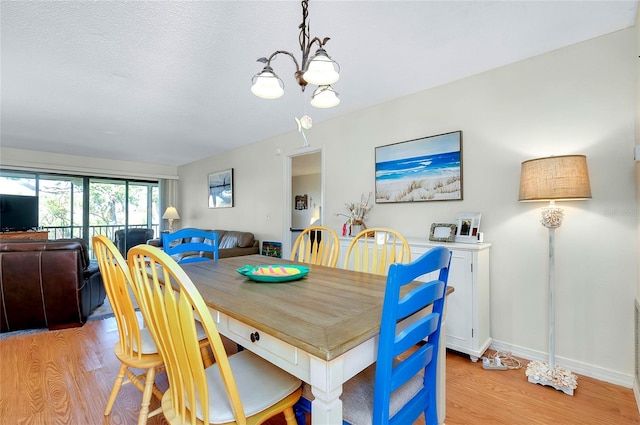 dining area with light hardwood / wood-style floors and a notable chandelier