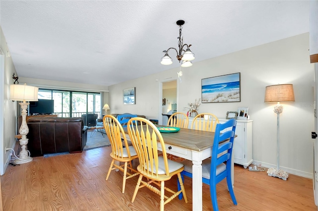 dining space featuring light hardwood / wood-style floors, a textured ceiling, and an inviting chandelier