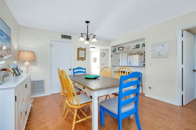 dining area featuring light hardwood / wood-style floors and a notable chandelier