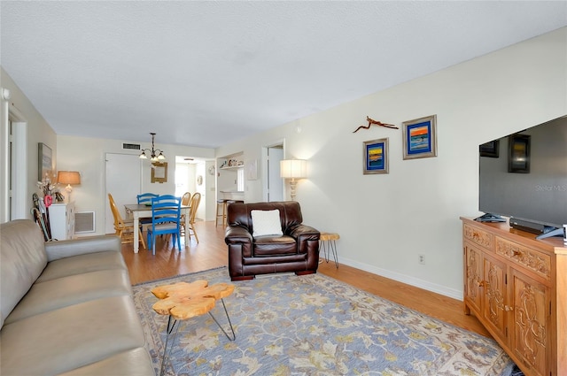 living room with light hardwood / wood-style floors and an inviting chandelier