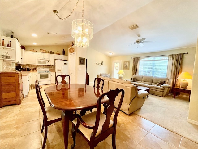 dining space with ceiling fan with notable chandelier, light tile patterned flooring, and lofted ceiling