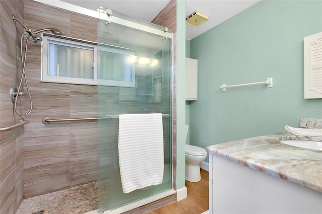 bathroom featuring toilet, a tile shower, and vanity