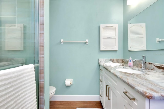 bathroom with hardwood / wood-style flooring, toilet, vanity, and an enclosed shower