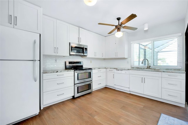 kitchen with appliances with stainless steel finishes, backsplash, light wood-type flooring, white cabinets, and sink