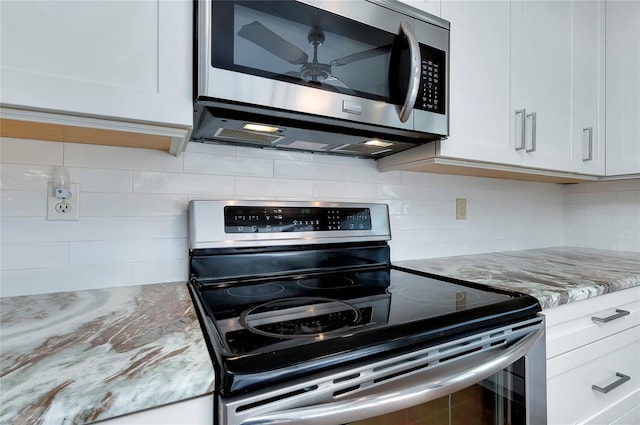 kitchen featuring decorative backsplash, light stone counters, stainless steel appliances, and white cabinetry