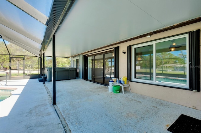 view of patio with a hot tub and glass enclosure