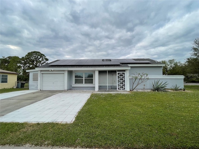 view of front of house featuring a garage, a front yard, and solar panels