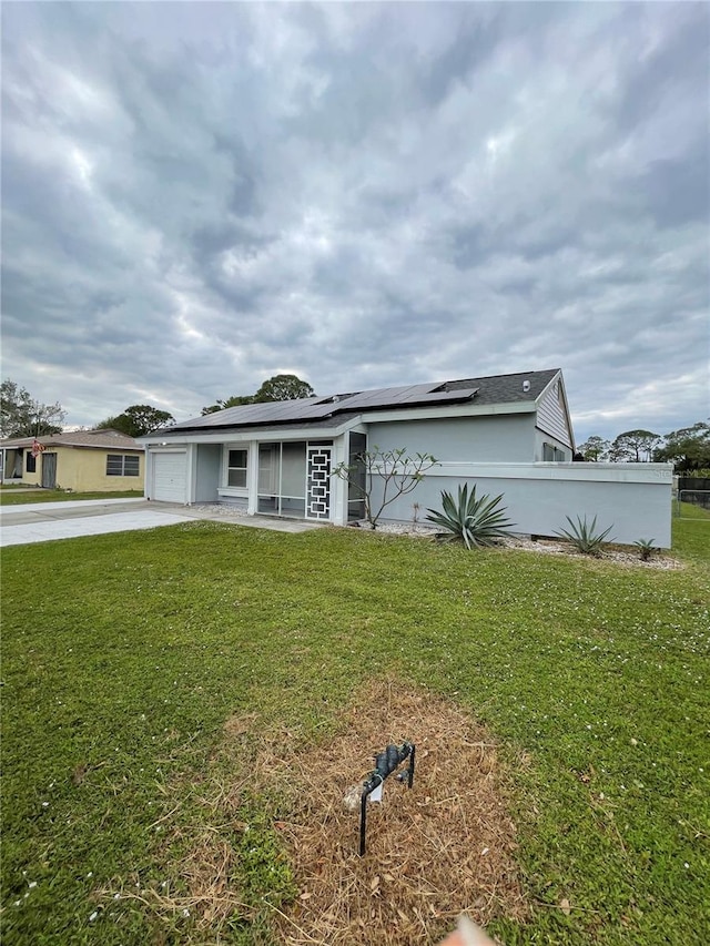 view of front of house featuring a front yard, solar panels, and a garage